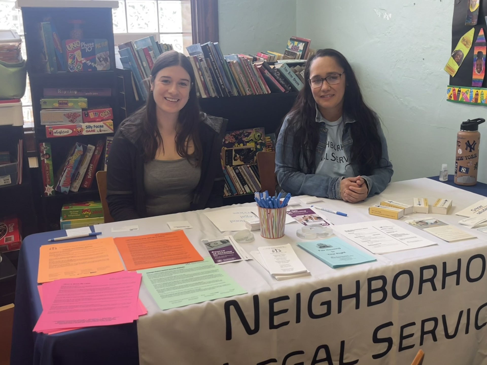 Two NLS team members sitting at our booth during an indoor tabling event