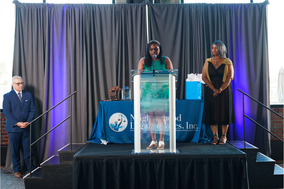 Board President Kerisha speaking at the 50th Anniversary Gala, with Bill and Lillie looking on.